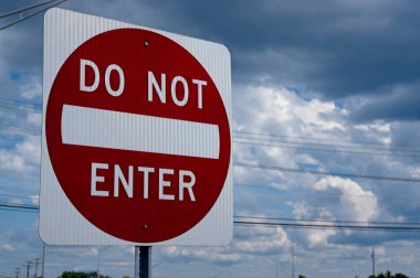 Bulutlu bir arkaplanda, elektrik hatları olan kırmızı ve beyaz Girilmez işareti