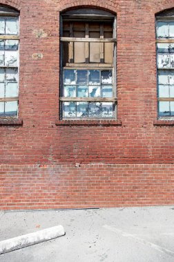 Terk edilmiş tuğla sanayi binası. Kırık ve hava şartları yüzünden park yerinin yanındaki camlar aşınmış.