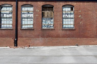 Terk edilmiş tuğla sanayi binası kırık ve hava şartları yüzünden camları aşınmış.