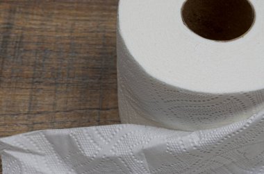 Tahta arka planda tuvalet kağıdı yuvarlanıyor.