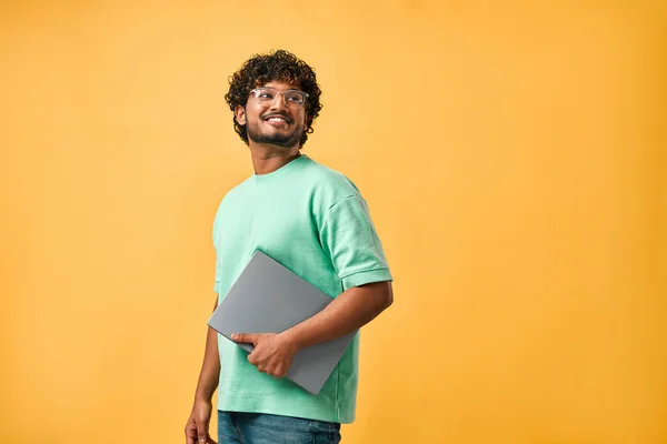 stock image Portrait of handsome curly Indian man in turquoise t-shirt and glasses laughing looking away and holding laptop. Copy space.