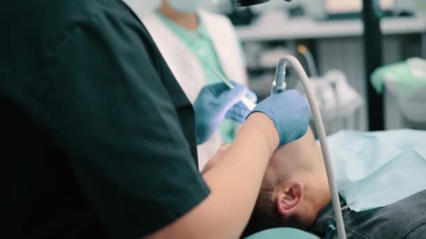 Mężczyzna Dentysta Używa Mikroskopu Podczas Leczenia Pacjenta Klinice Kobieta Asystentka — Wideo stockowe