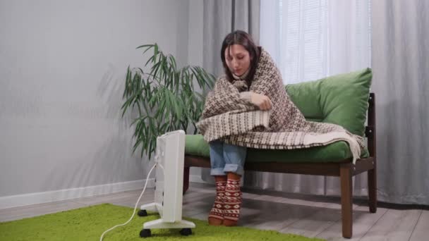 一位穿着温暖的年轻女性在家里的电暖炉旁取暖 — 图库视频影像