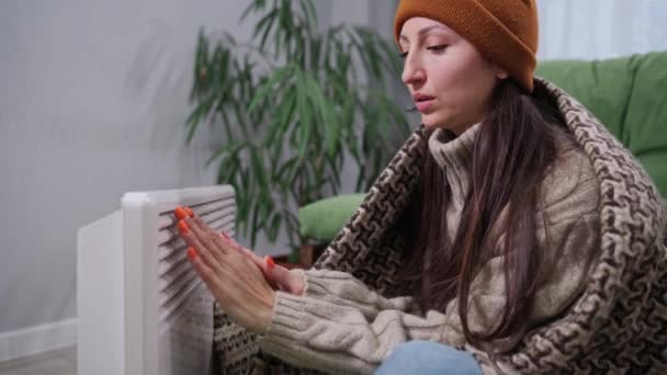 一位穿着温暖的年轻女性在家里的电暖炉旁取暖 — 图库视频影像