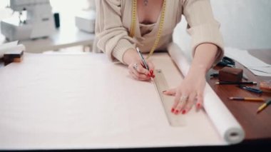 Giysi tasarımcısı atölyede desenler çizer. Eller yukarı..