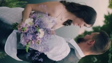 Sevgi dolu yeni evliler. Damat gülen gelinini öper. Dikey video.