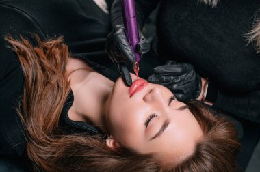 Kalıcı dudak makyajı. Kozmetik uzmanı, kuafördeki müşteriye kalıcı makyaj prosedürünü uygular..