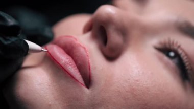 Permanent lip makeup. Beautician makes lip contour marks. Extreme close-up.