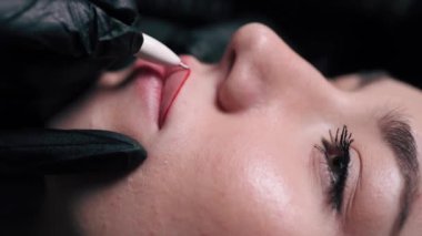 Permanent lip makeup. Beautician makes lip contour marks. Extreme close-up.