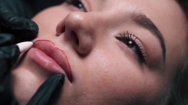 Permanent lip makeup. Beautician makes lip contour marks. Extreme close-up.
