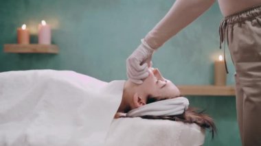 Kozmetik uzmanı spa 'daki hastaların yüz kaslarına Bucik masaj yapıyor. Yaşlanma karşıtı masaj tekniği. Yan görünüm.