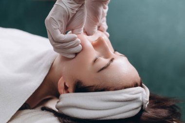 Kozmetik uzmanı spa 'daki hastaların yüz kaslarına Bucik masaj yapıyor. Kapat..
