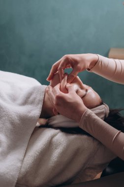 Güzellik uzmanı genç bir kadına derin bir yüz masajı yapıyor. Yaşlanmaya karşı yüz masajı tekniği. Yakın plan..