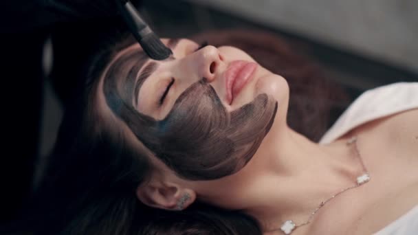 Cosmetolog Aplicando Máscara Negra Cara Mujer Bonita Mujer Spa Con — Vídeos de Stock