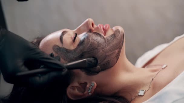 Cosmetolog Die Een Zwart Masker Haar Gezicht Aanbrengt Vrouw Spa — Stockvideo