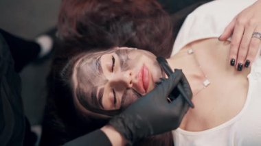 Kozmetik uzmanı güzel kadın yüzüne siyah maske takıyor. Kaplıcada yüz ameliyatı olan bir kadın. Üst görünüm.
