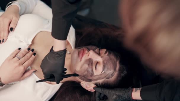 Kosmetolog Nakładający Czarną Maskę Piękną Kobiecą Twarz Kobieta Spa Zabiegi — Wideo stockowe