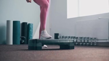 Basamak platformunda egzersiz yapan bir kadın. Spor salonunda kadın bacaklarının aktif eğitimi. Bacaklarını kapat..