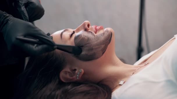 Cosmetolog Applicera Svart Mask Vacker Kvinna Ansikte Kvinna Spa Med — Stockvideo