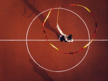 Young female gymnast exercising with ribbon, top view.