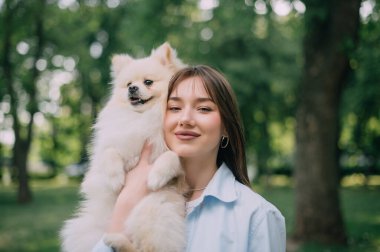 Köpeğiyle birlikte genç bir kadının portresi. Pomeranian, sahibinin elinde..
