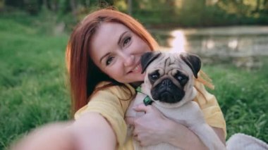 Mutlu kadın köpeğiyle selfie çekiyor. Bir kadın kollarında bir köpek taşıyor. Komik köpek kameraya bakıyor. POV.