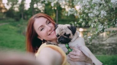 Mutlu kadın köpeğiyle selfie çekiyor. Bir kadın kollarında bir köpek taşıyor. Komik köpek kameraya bakıyor. POV.