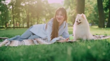Genç bir kadın çimlere uzanıyor ve Pomeranya köpeğini kollarında tutuyor. İşaret fişeği etkisi.