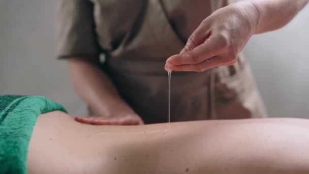 Masajista Aplica Aceite Piel Espalda Cerca Una Mujer Relaja Una — Vídeo de stock