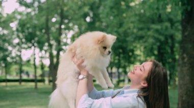 Genç ve mutlu bir kadının köpeğiyle portresi. Pomeranian, sahibinin elinde..