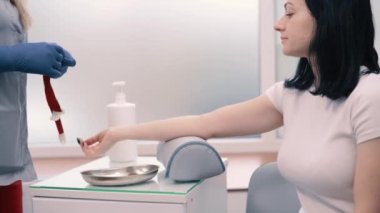 Laboratuvar çalışanı doktor analiz için kan örneği alıyor. Genç bir kadın klinikte analiz için damardan kan bağışlıyor..