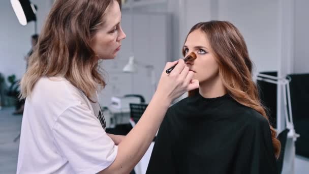 Makeup Artist Tillämpar Foundation Med Borste Ansiktet Ung Kvinna Salong — Stockvideo