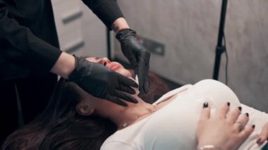 Güzellik salonunda bir kadın. Bir kozmetikçi müşterilerin yüzünü pamukla siliyor..