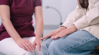 Kadın doktor hastaların elini tutuyor. Bir hemşire klinikteki genç bir kadına manevi destek sağlar. Eller yukarı..