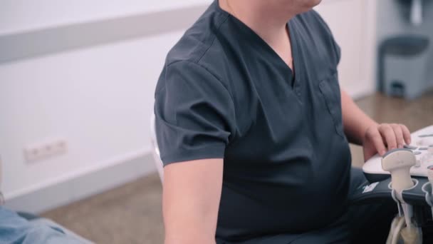 의사는 병원에서 여성의 갑상선 초음파 스캔을 수행합니다 여성은 검사를 있습니다 — 비디오