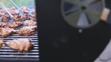 Et ızgara. Aşçı tavuklu filetoyu maşayla çevirir. Yakın plan..