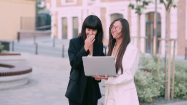 İki iş kadınıyla tanışmak. İş kıyafetleri giymiş iki genç kadın şehir caddesinde dizüstü bilgisayar kullanarak bir projeyi tartışıyorlar..