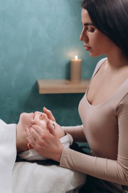 Güzellik uzmanı genç bir kadına derin bir yüz masajı yapıyor. Yaşlanmaya karşı yüz masajı tekniği. 