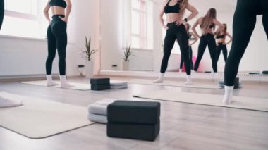 Beden eğitiminde grup çalışması. Bir grup genç zayıf kadın ısınma turu yapıyor. Antrenör egzersizleri gösterir..