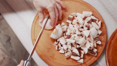 Evdeki mutfakta taze mantarları ince ince doğrayan bir kadın. Üst görünüm.