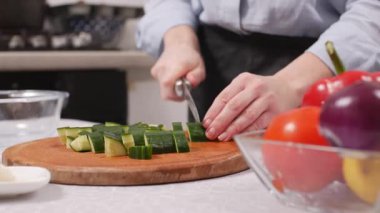 Kadın salata için taze sebze kesiyor. Yakın plan. Kadın mutfakta yemek hazırlıyor..