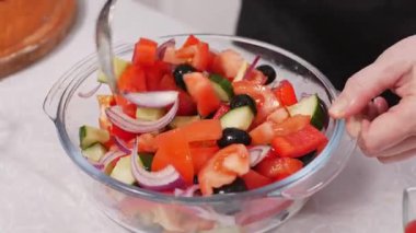 Mutfakta cam kasede Yunan salatası malzemelerini karıştıran bir kadın. Kapat..