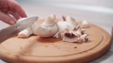 Evdeki mutfakta taze mantarları ince ince doğrayan bir kadın. Ellerin yakın çekimi.