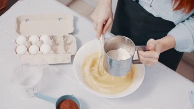 Bir kadın para kazanır. Dişi, un ve yumurtayı evde çırpma makinesiyle karıştırıyor. Üst görünüm.