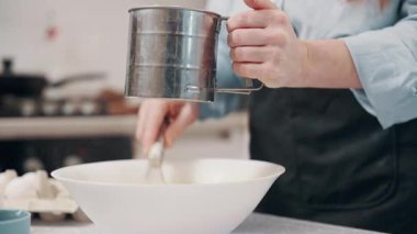 Bir kadın para kazanır. Dişi, un ve yumurtayı evde çırpma makinesiyle karıştırıyor. Kapat..