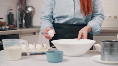 Yemek hazırlayan kadın. Kadın mutfakta cam kaseye yumurta kırıyor.. 