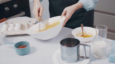 Kadın ev yemeği hazırlıyor. Kadın, evdeki mutfakta bir kasede yumurta çırpıyor. Yakın plan..