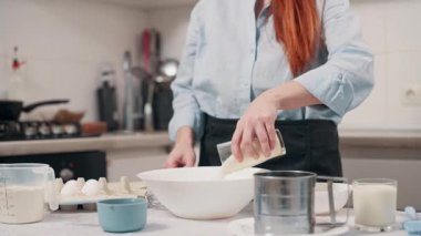 Bir kadın para kazanır. Kadın malzemeleri evdeki mutfakta bir kasede karıştırıyor.. 