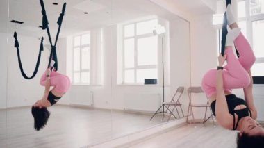 İnce vücutlu bir kız spor salonunda esnek kumaş üzerinde egzersiz yapıyor. Yavaş çekim.