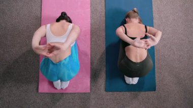 Spor salonunda pilates yapan iki genç atletik kadın. Antrenör egzersizin doğru uygulandığını gösteriyor. Üst görünüm.